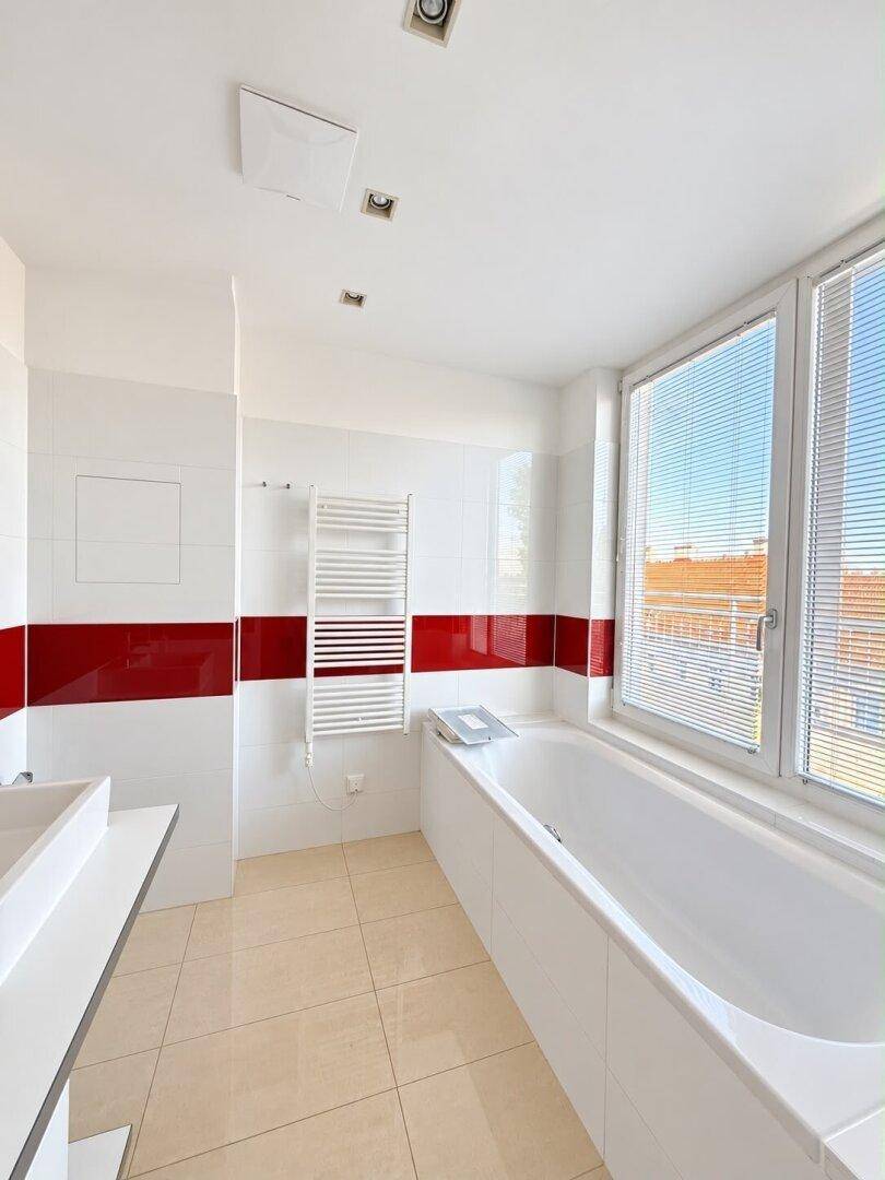 Modernes Badezimmer mit Badewanne, Waschbecken und Fenster, bereit zur individuellen Gestaltung.