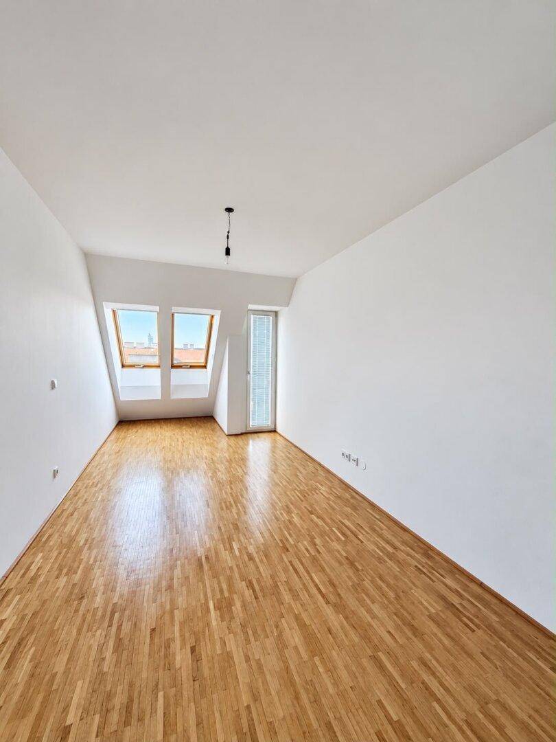 Helles Schlafzimmer mit Holzboden, Dachschrägen und zwei Dachfenstern für viel Licht.