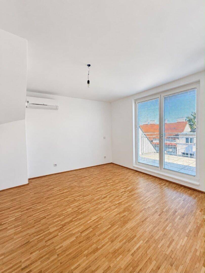 Geräumiges Schlafzimmer mit Holzboden, großen Fenstern und Klimaanlage.