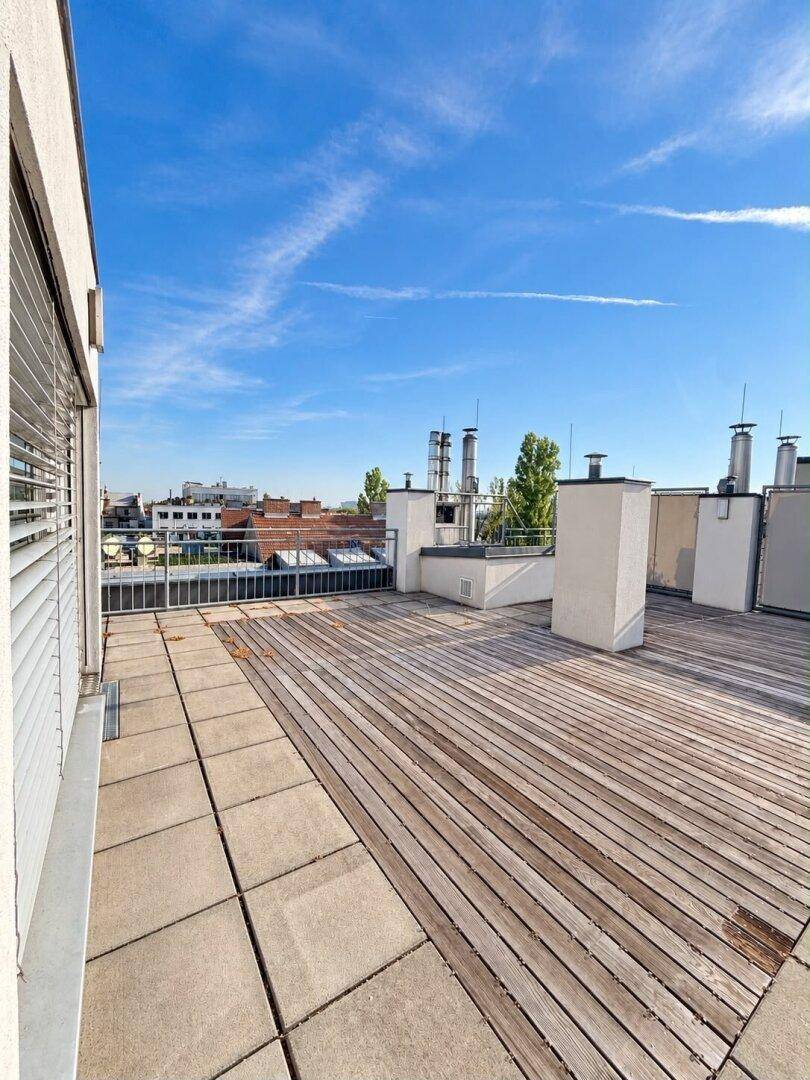 Weitläufige Dachterrasse mit Holz- und Fliesenbereichen, ideal für Entspannung im Freien.