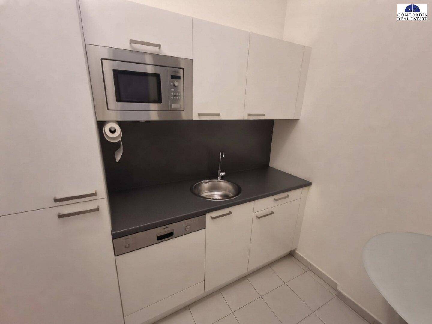 Kompakte Küchenzeile mit Mikrowelle, Spülmaschine und Spüle, ideal für kleine Büros.