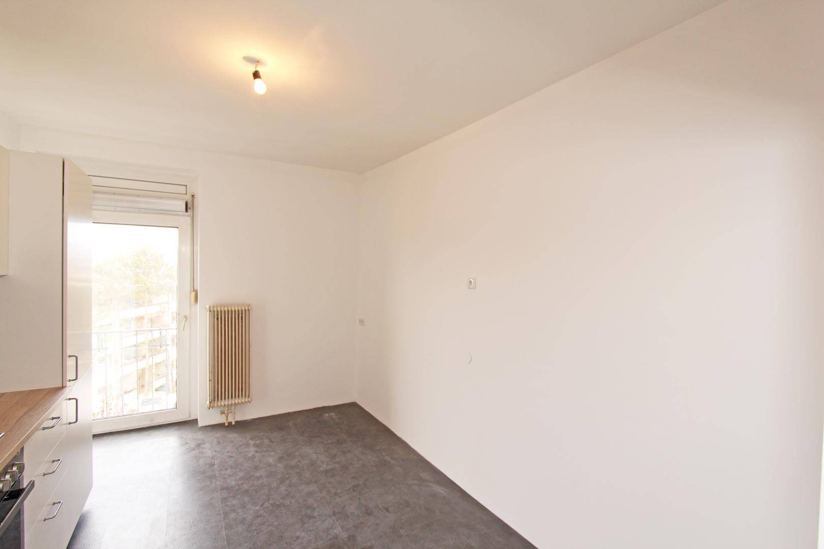 Heller Essbereich neben der Küche mit Zugang zum Balkon und Heizkörper.