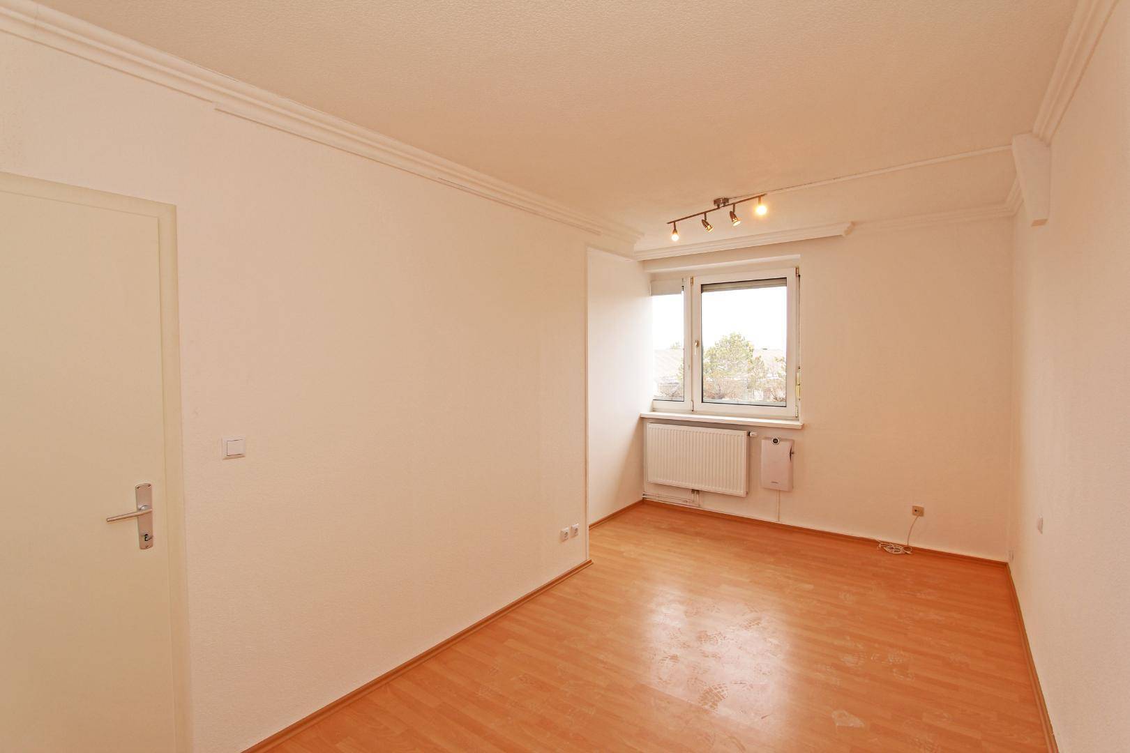 Weiteres helles Zimmer mit Parkettboden und Fenster, ideal als Schlaf- oder Arbeitszimmer.