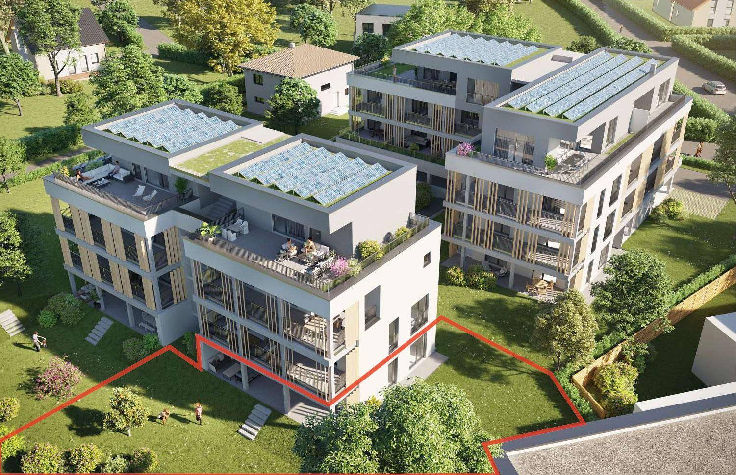 Luftaufnahme eines modernen Wohnkomplexes mit mehreren Gebäuden und Grünflächen, umrandet von einer roten Linie.