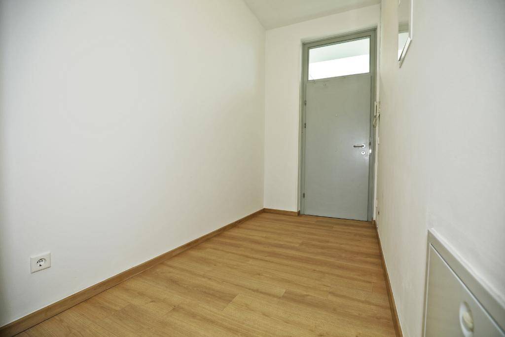 Schmaler Flur mit Laminatboden und einer Tür, die zu weiteren Räumen führt.