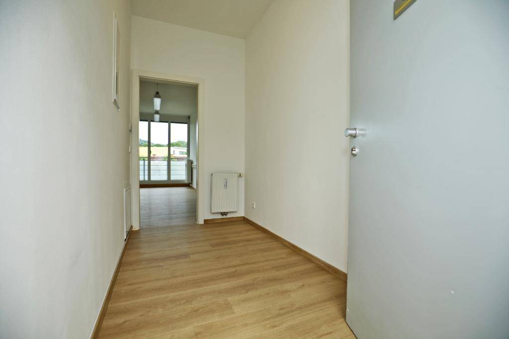 Heller Flur mit Laminatboden und Blick auf den Eingangsbereich mit großen Fenstern.