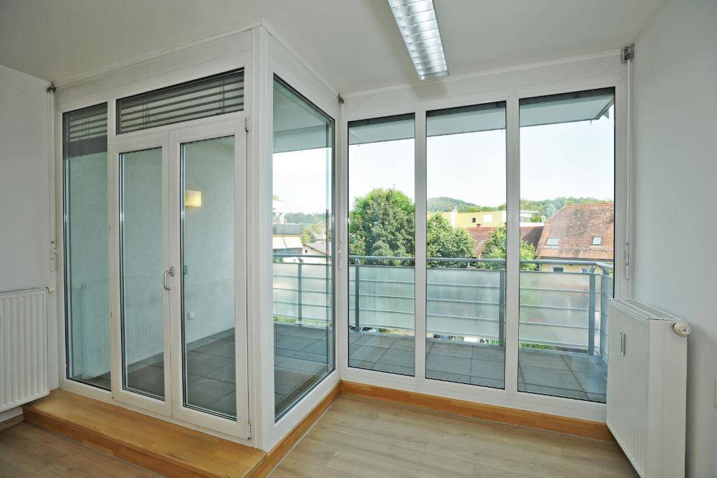 Heller Innenraum mit großen Fenstern, die viel Tageslicht hereinlassen und einen Blick nach draußen bieten.