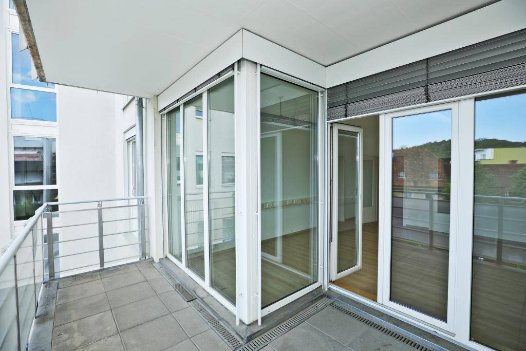 Balkon mit Fliesenboden und großen Glasfronten, die den Zugang zum Innenbereich ermöglichen.