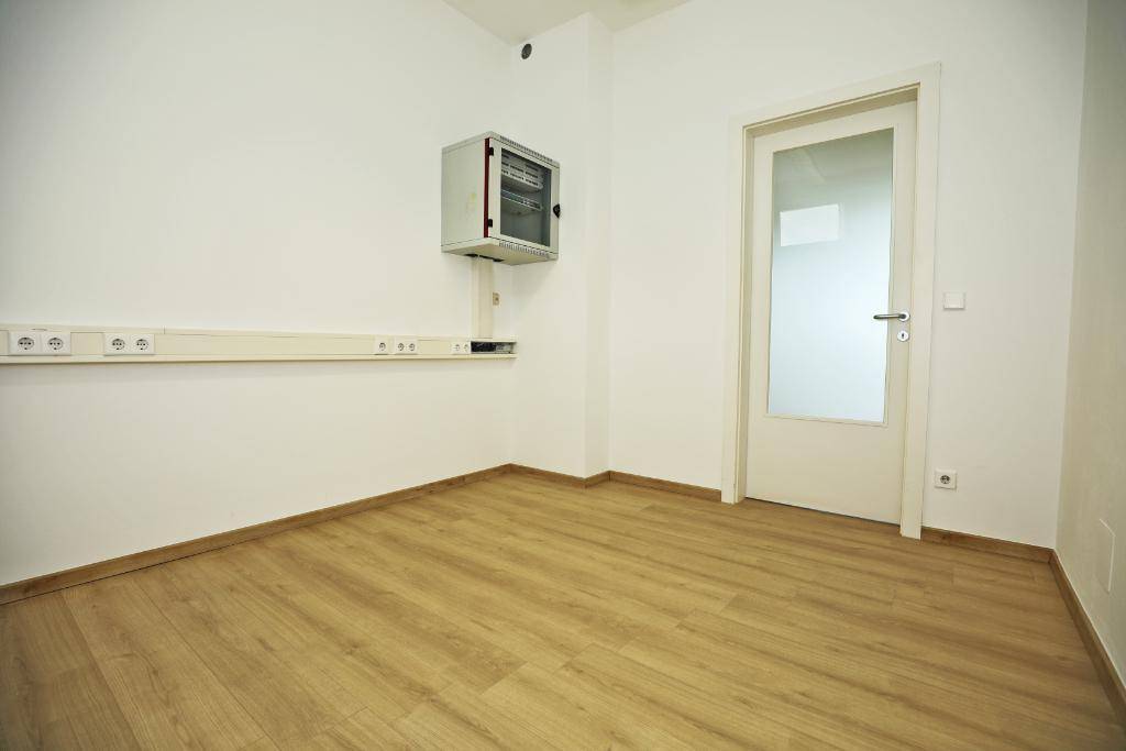 Kleiner Raum mit Laminatboden, weißer Wand und einer Tür mit Glaseinsatz.