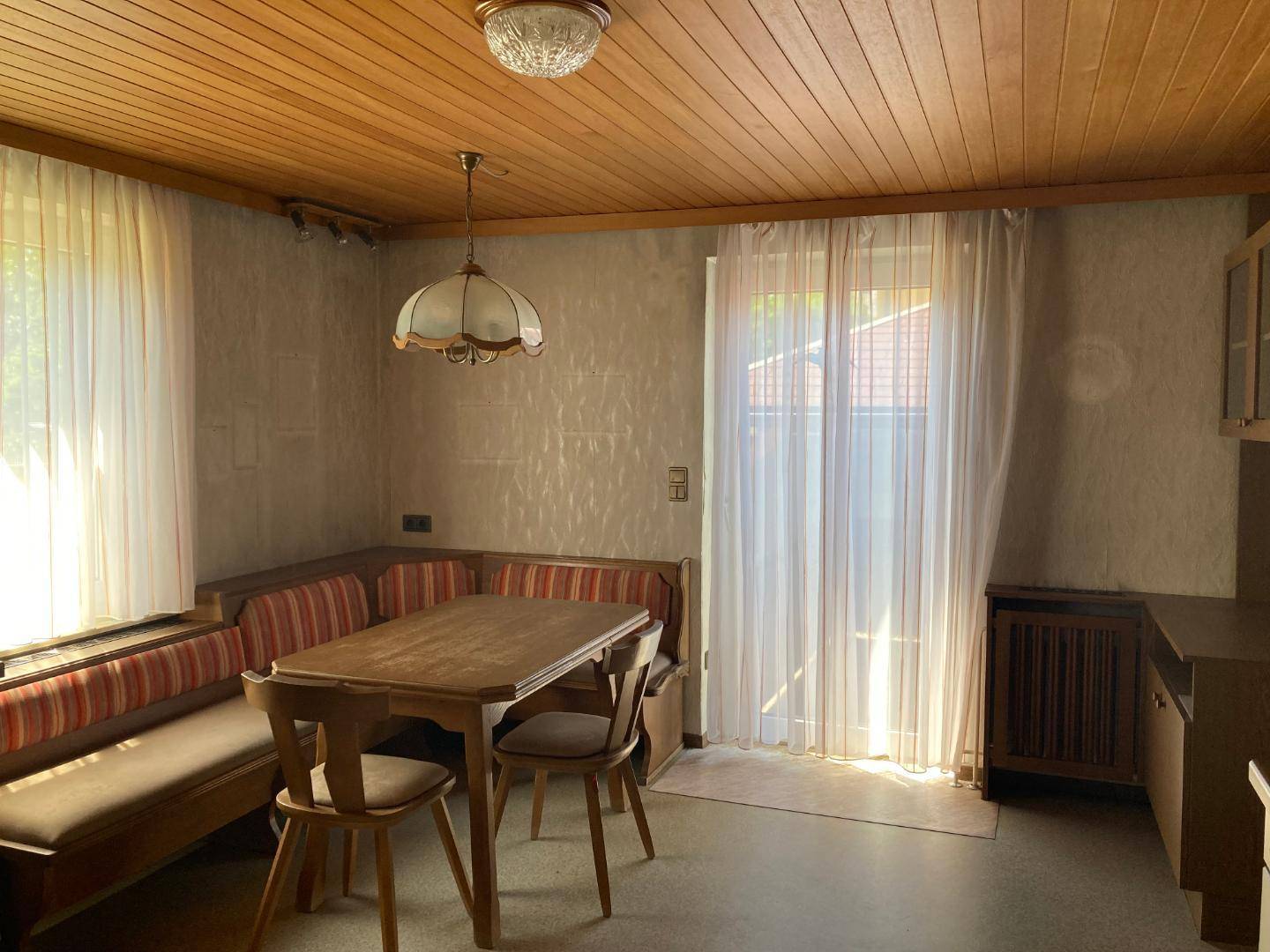 Gemütlicher Essbereich in der Küche mit Holztisch, Eckbank und Holzdecke.