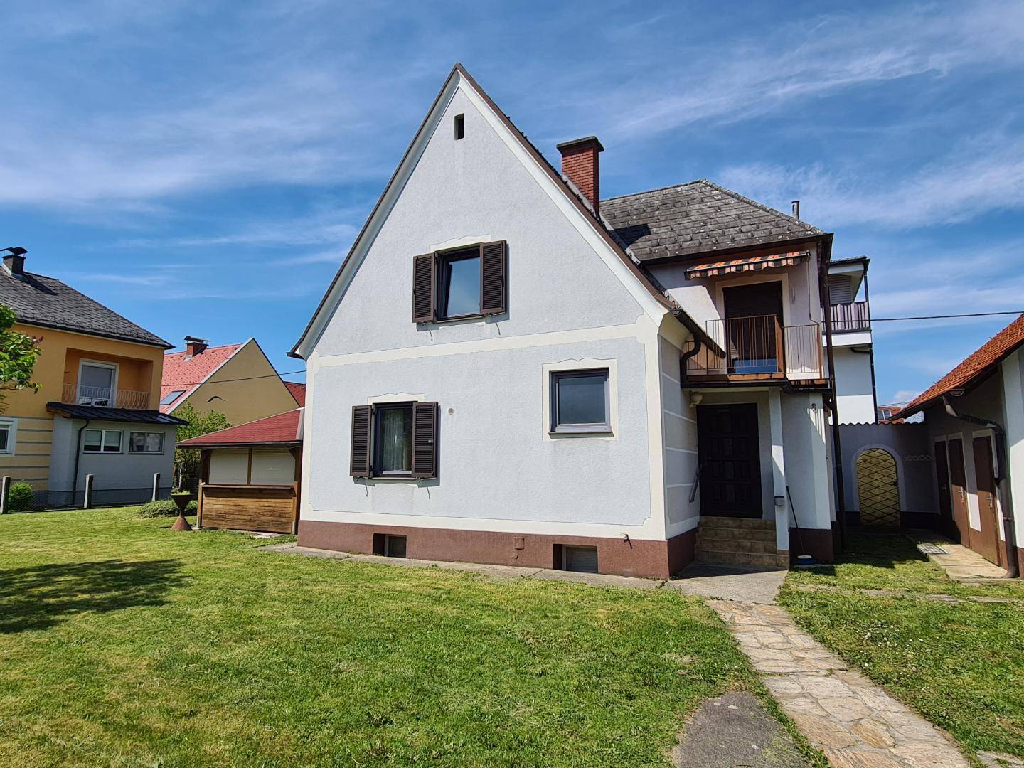 Vorderansicht des Einfamilienhauses mit Satteldach und großem Gartenbereich.