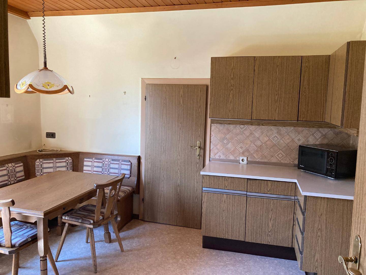 Küche mit Essbereich, Holzschränken, Mikrowelle und traditioneller Einrichtung.