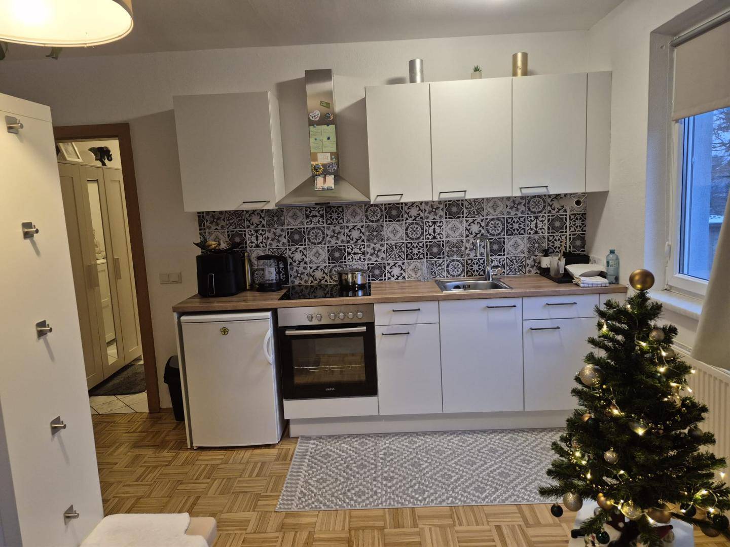 Funktionale Küche mit Holzarbeitsplatte, integrierten Geräten und festlicher Weihnachtsdekoration.