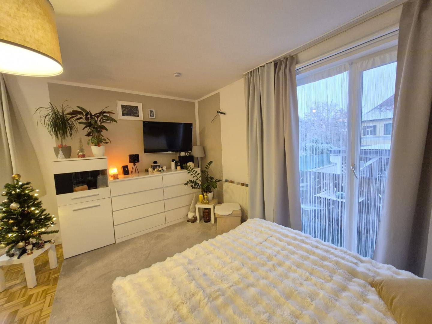 Gemütliches Schlafzimmer mit Teppichboden, großem Bett und festlicher Weihnachtsdekoration.