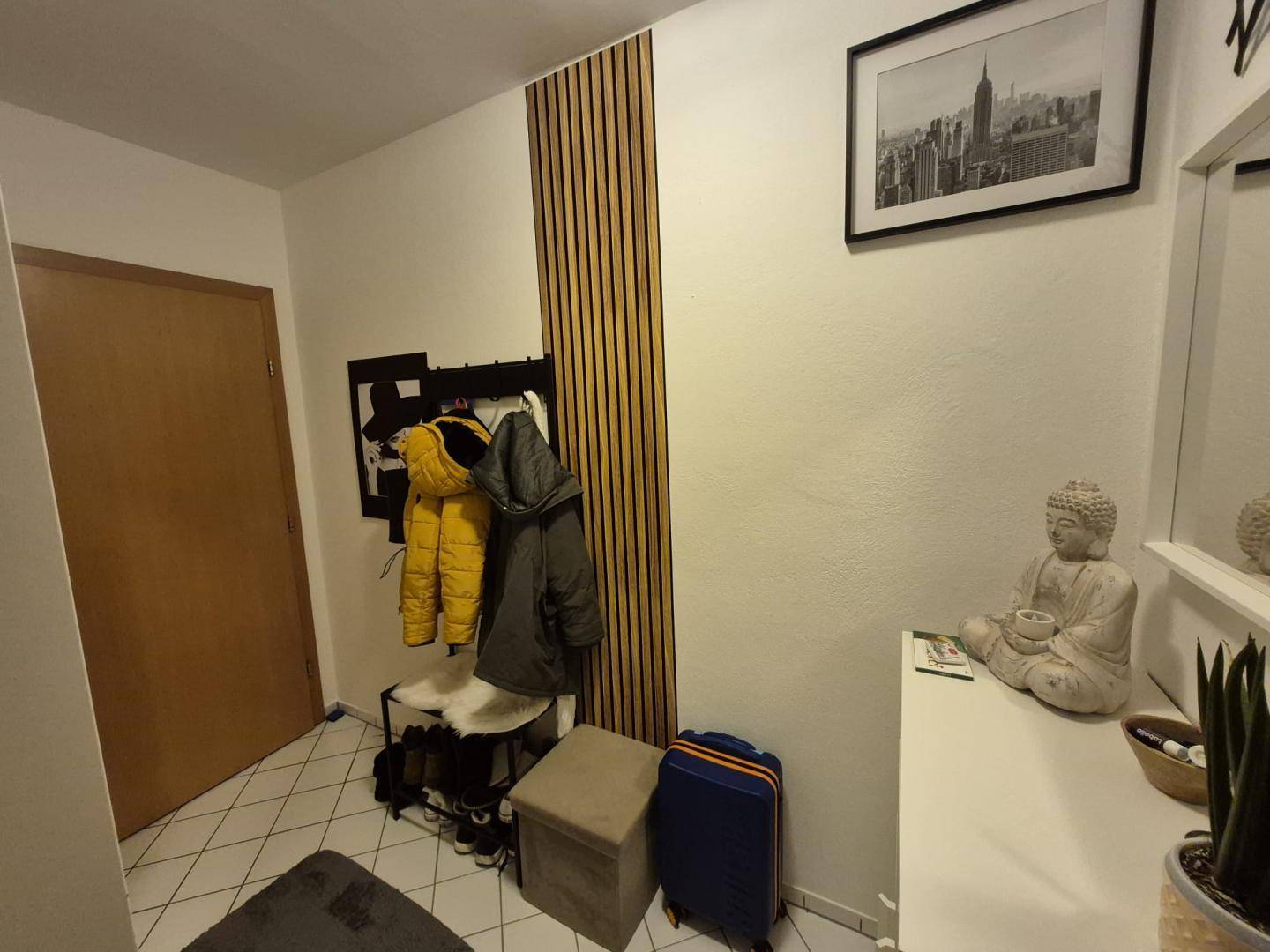 Heller Flur mit Fliesenboden, Garderobe und dekorativen Holzakzenten an der Wand.
