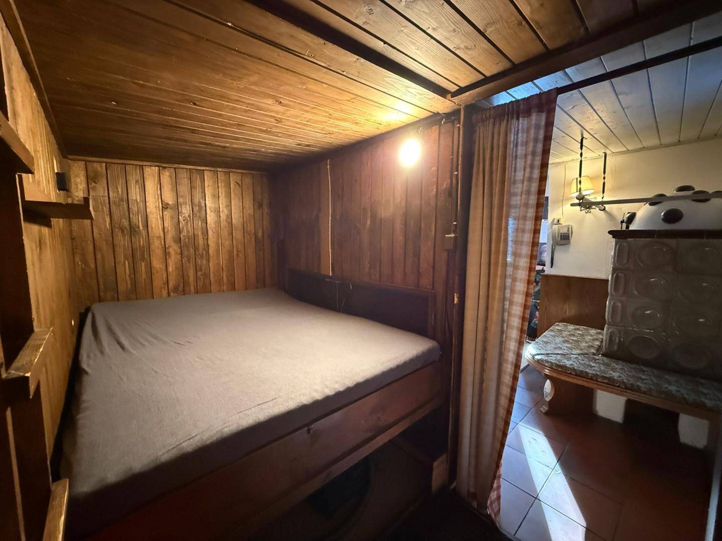 Kleiner, holzvertäfelter Schlafbereich mit einem Doppelbett, der Gemütlichkeit und Wärme ausstrahlt.