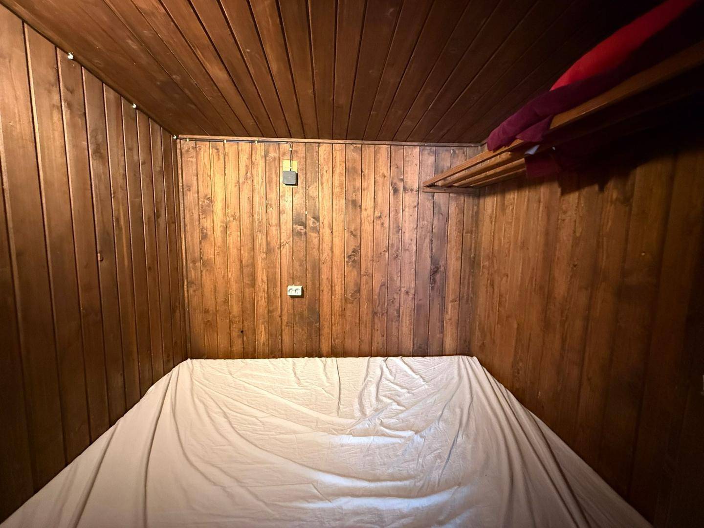 Kleiner, holzvertäfelter Schlafbereich mit einem Doppelbett, der Gemütlichkeit und Wärme ausstrahlt.