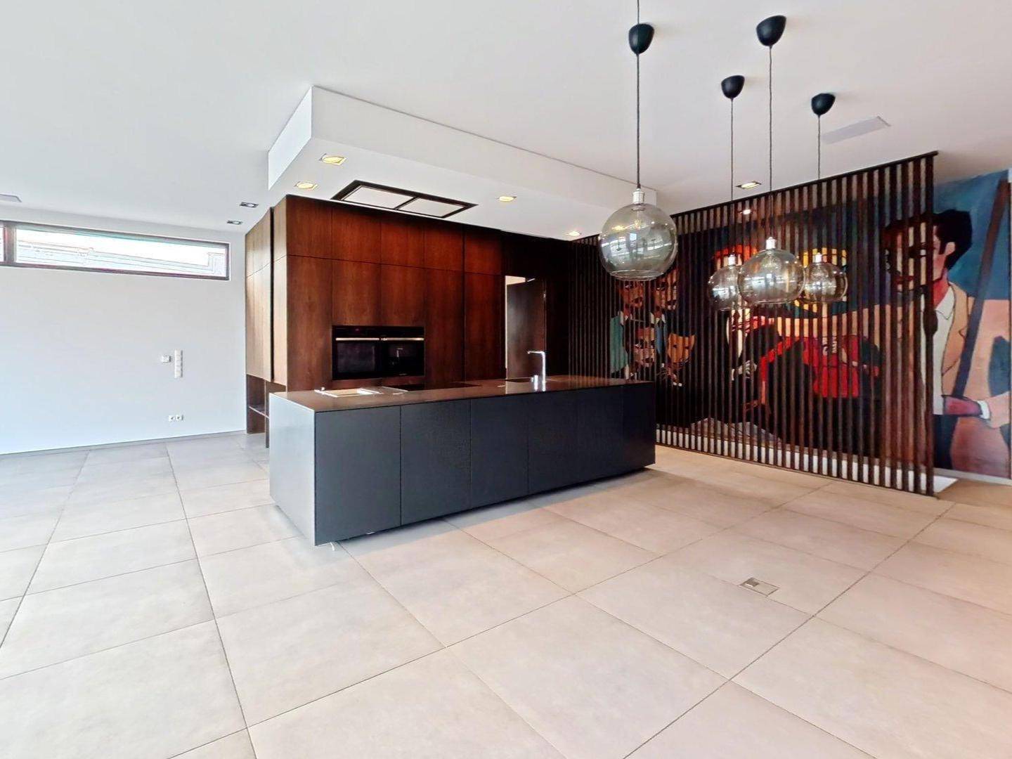 Moderne Küche mit dunkler Kücheninsel, Holzakzenten und integrierten Geräten.