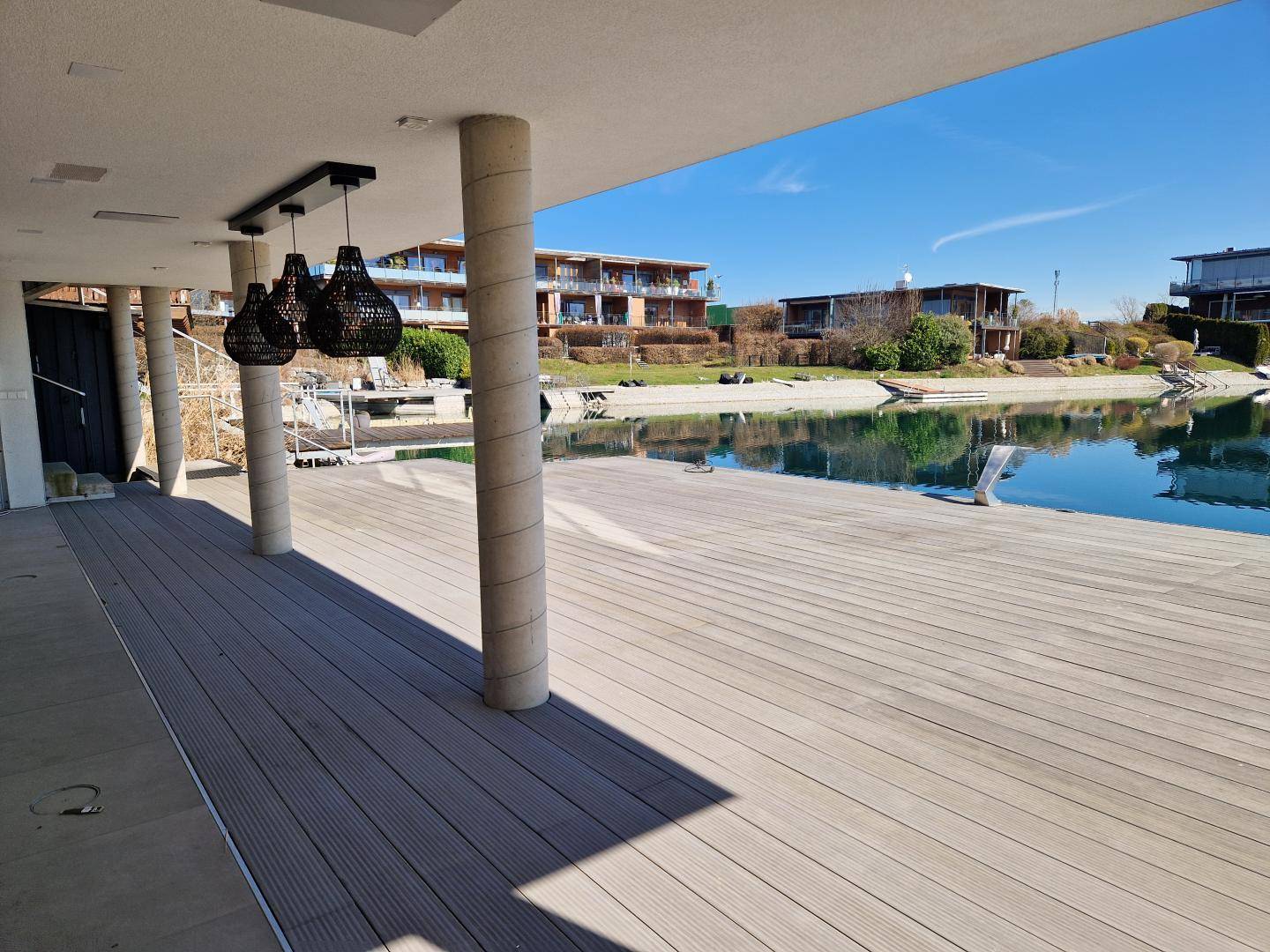 Überdachte Terrasse mit Säulen und Blick auf den See, ideal für entspannte Stunden im Freien.
