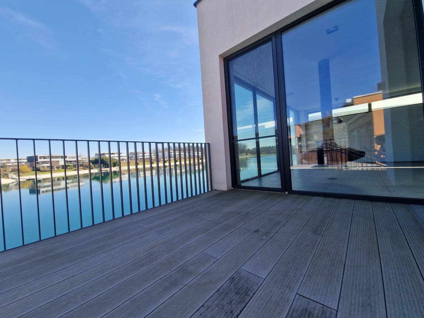 Geräumiger Balkon mit Holzboden und weitem Blick über den See und die Umgebung.