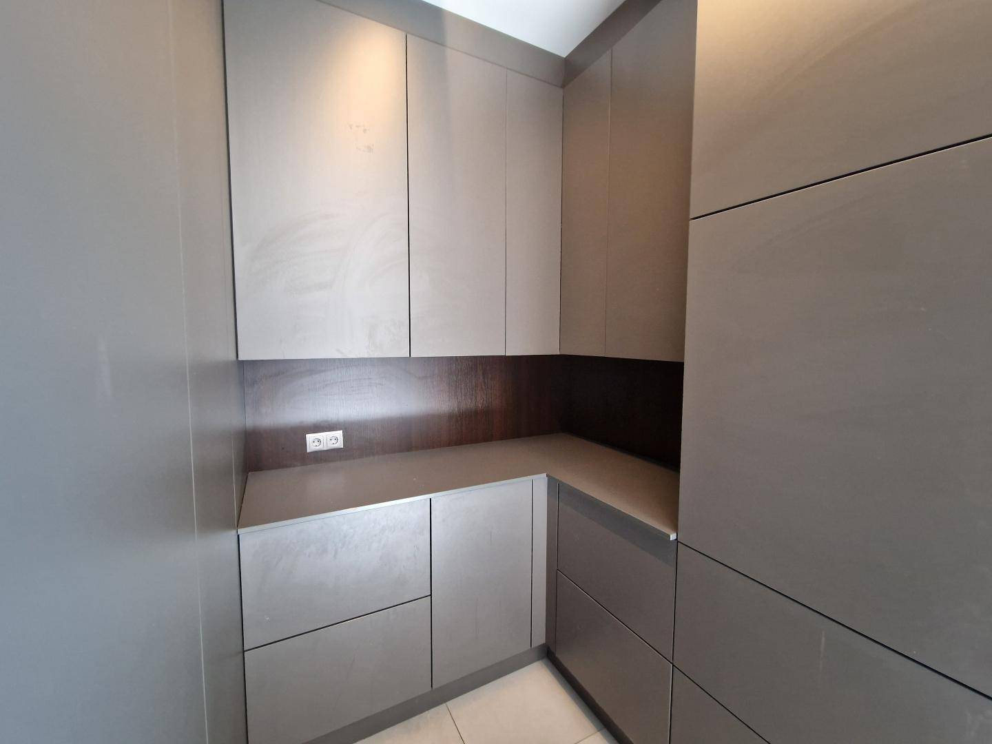 Praktischer Abstellraum mit modernen grauen Einbauschränken und Arbeitsfläche.