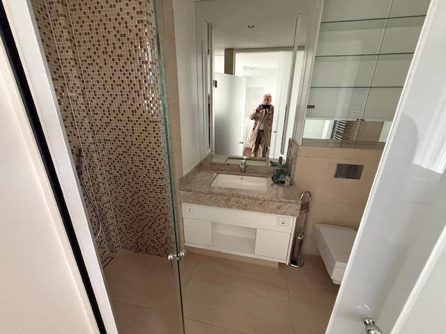 Modernes Badezimmer mit Mosaikfliesen in der Dusche und Einzelwaschbecken.