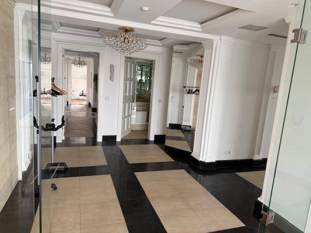 Eleganter Eingangsbereich mit glänzenden Fliesen, hohen Decken und Kronleuchter.
