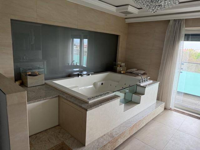 Luxuriöses Badezimmer mit eingelassener Whirlpool-Badewanne und Terrassenzugang.