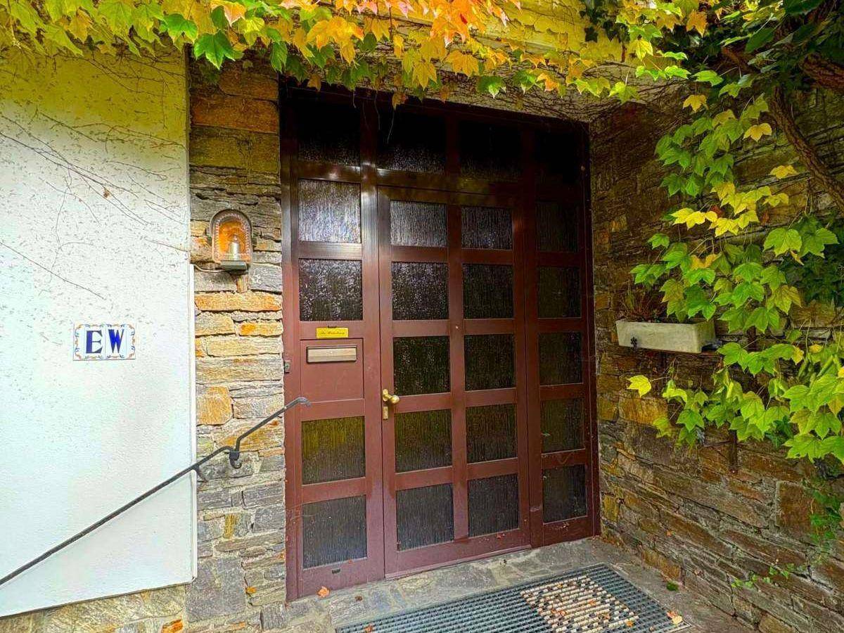 Eingangsbereich des Hauses mit rustikaler Steinfassade und Holztür.