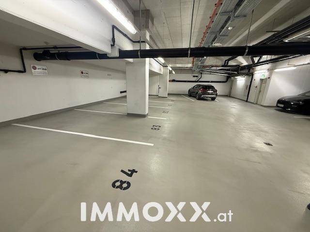 Tiefgarage mit markierten Stellplätzen und Beleuchtung.