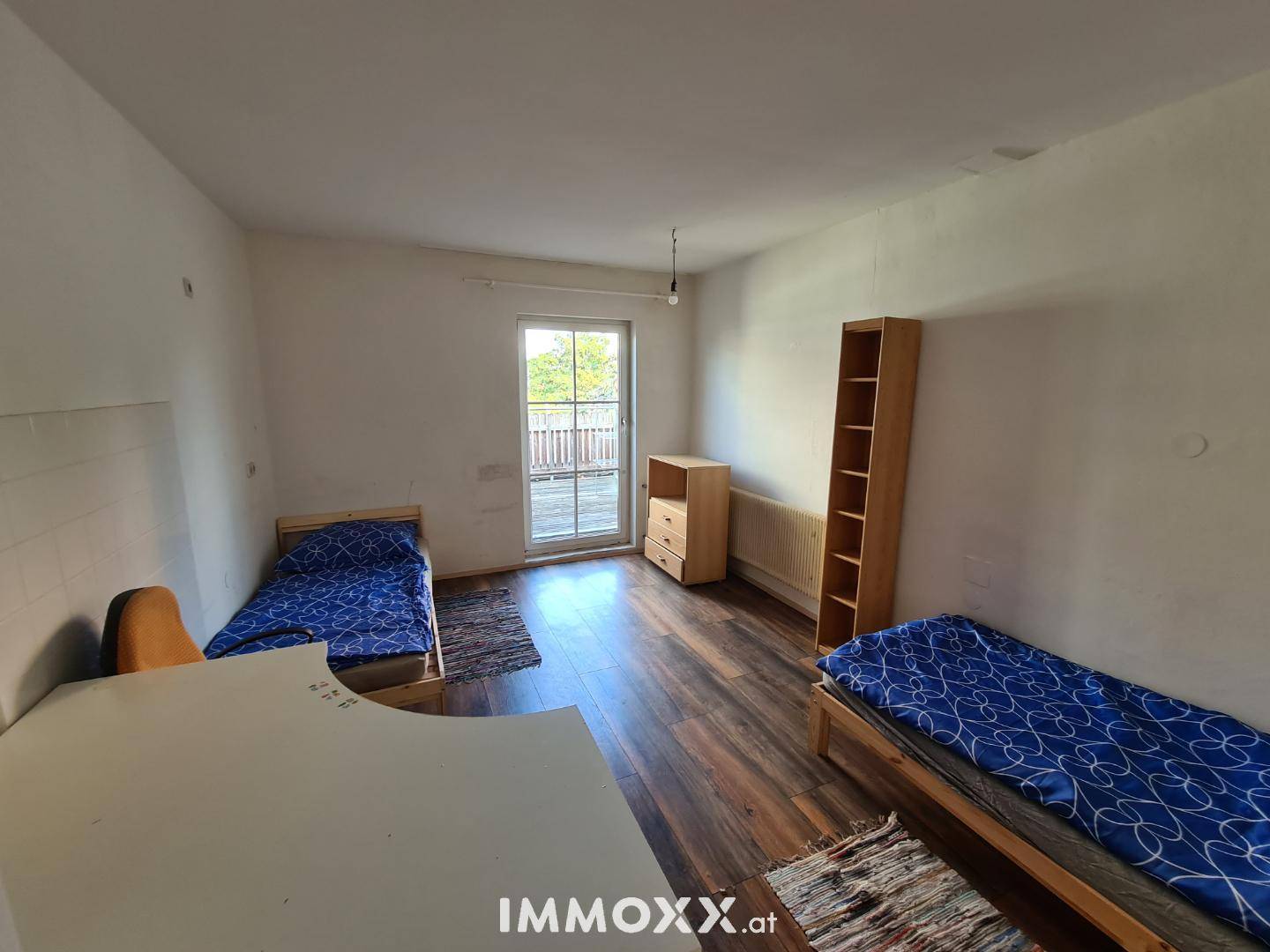 Helles Schlafzimmer mit zwei Einzelbetten, Holzmöbeln und direktem Zugang zur Terrasse.