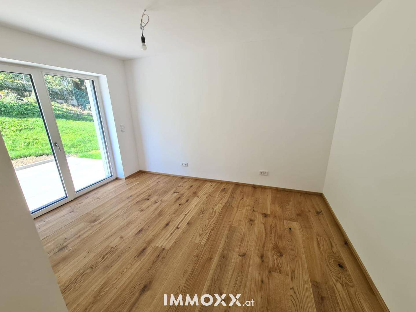 Heller Raum mit Eichenparkettboden und großem Glaszugang zur Terrasse oder zum Garten.