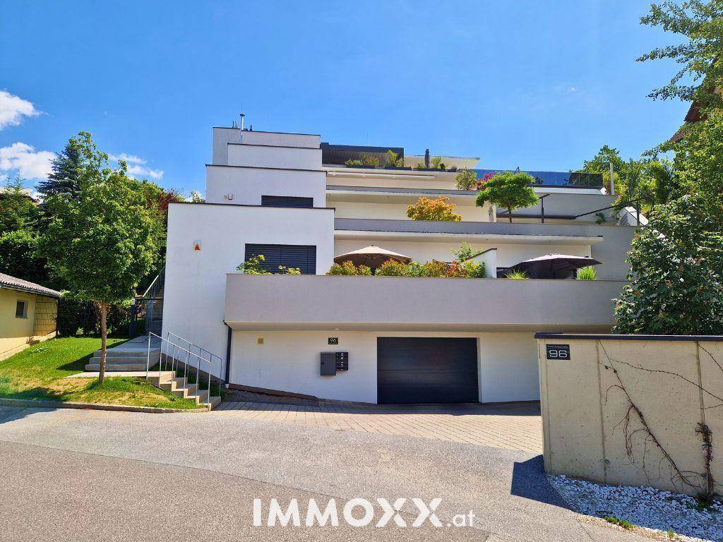 Ansicht des modernen Wohngebäudes mit mehreren Terrassen und Garagenzufahrt.