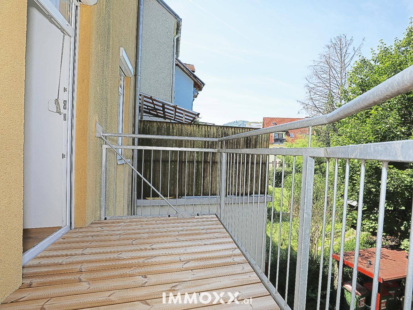 Neuer Balkon mit Holzbelag und Metallgeländer, bietet einen Blick auf die Umgebung.