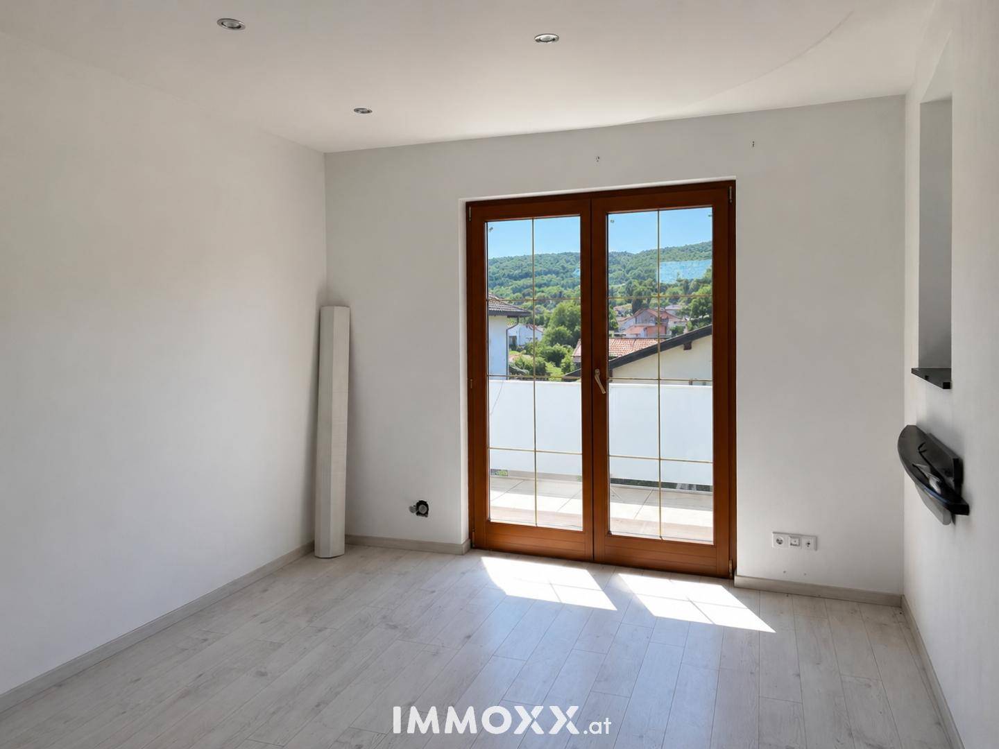 Heller Raum mit großen Fenstertüren, die einen malerischen Blick auf den See und die Umgebung bieten.
