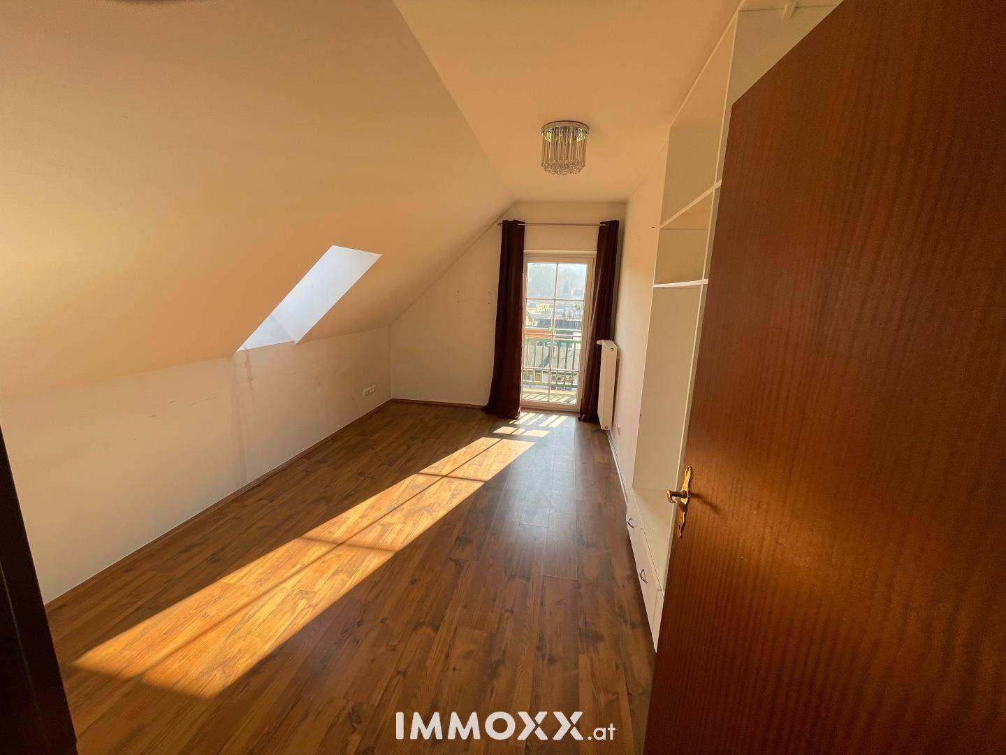 Schlafzimmer im Dachgeschoss mit Laminatboden, Dachschräge, Dachfenster und Balkonzugang.