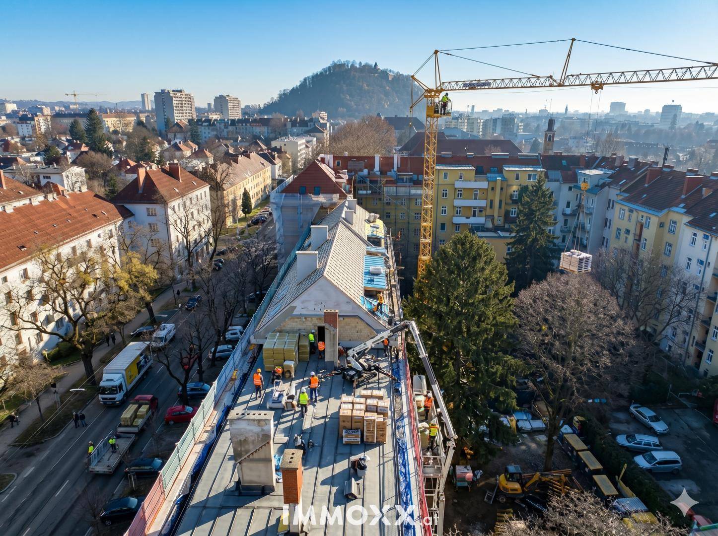 Luftaufnahme einer Baustelle auf einem Dach mit Blick über die Stadt und Hügel.
