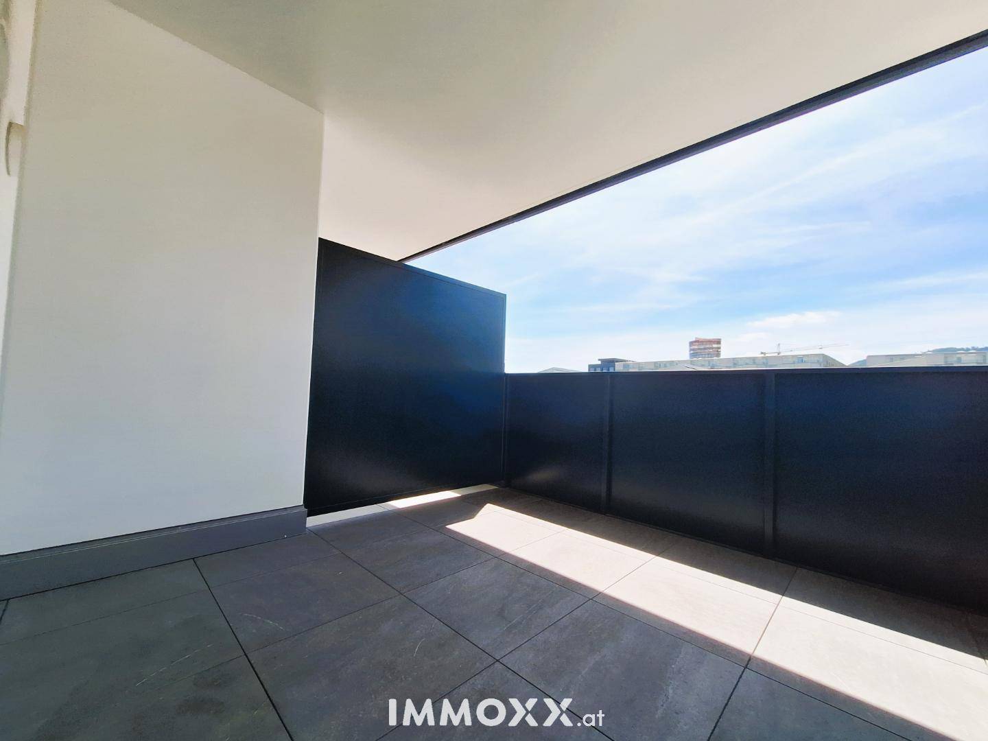 Geräumiger Balkon mit Fliesenboden und hoher Brüstung, bietet Privatsphäre.