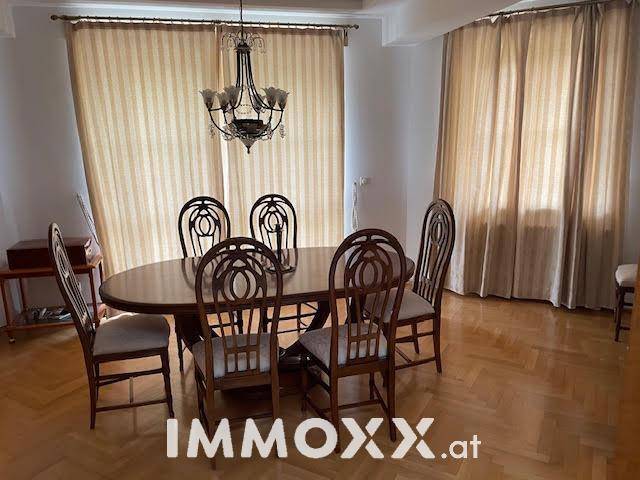 Klassisches Esszimmer mit großem Holztisch, passenden Stühlen und einem eleganten Kronleuchter.