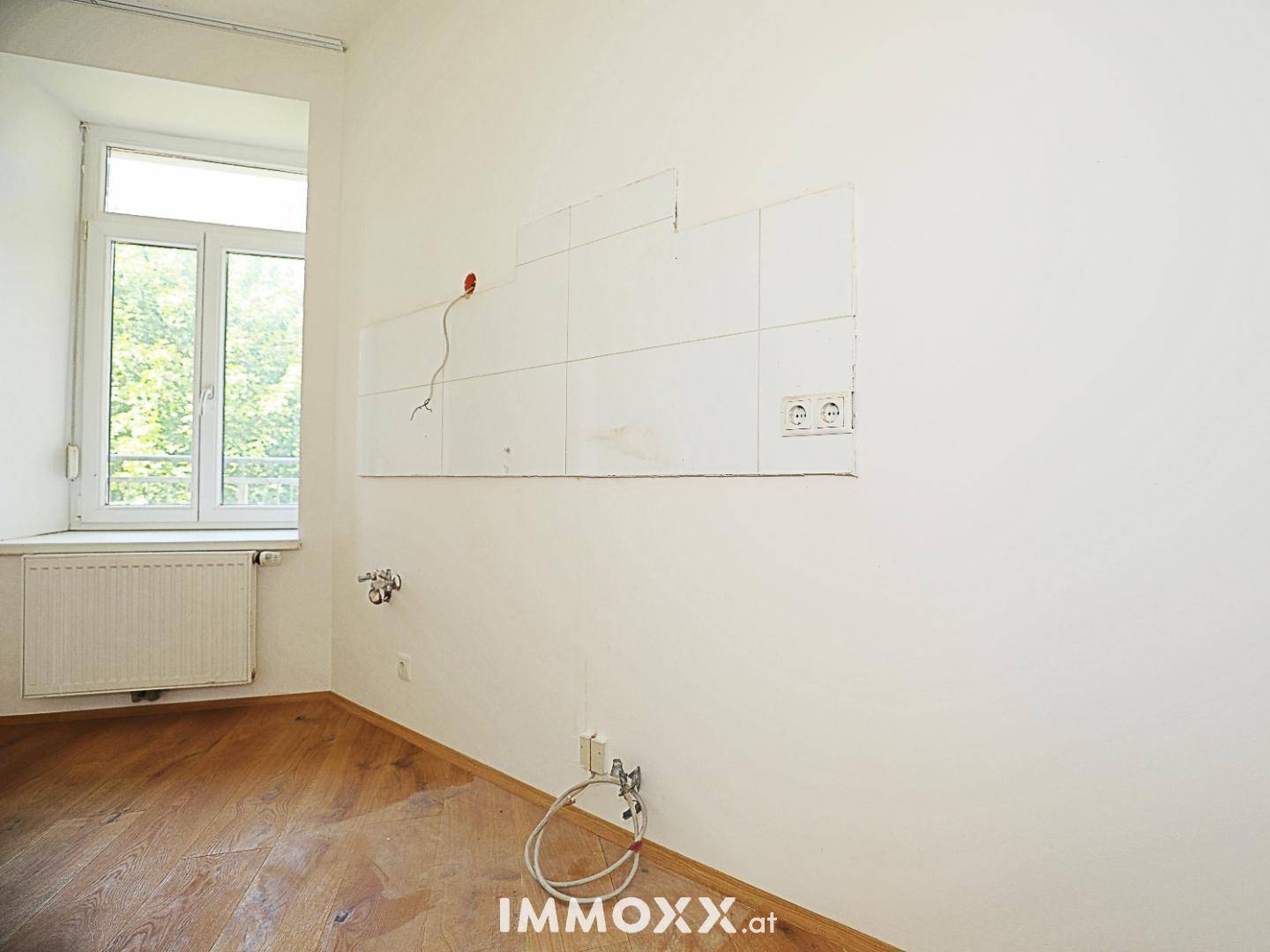 Leerer Küchenbereich mit vorbereiteten Anschlüssen und Fliesen an der Wand, mit Fenster.