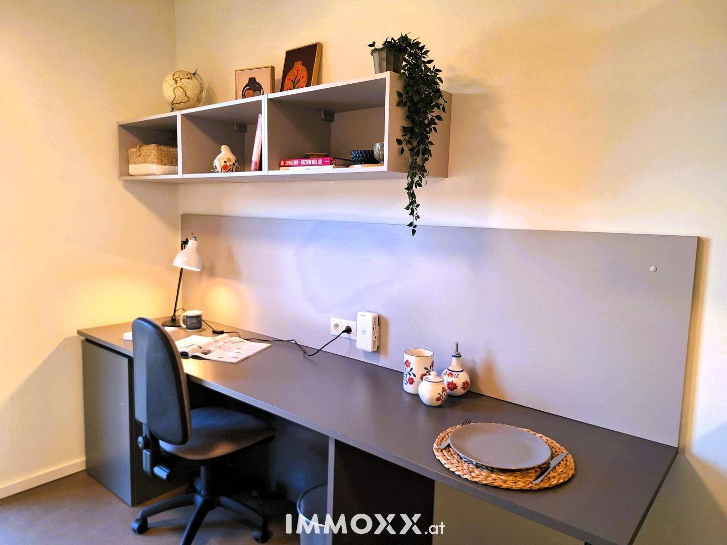 Heller Arbeitsbereich mit Schreibtisch, Regal und moderner Dekoration.