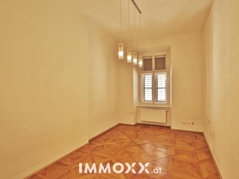 Heller Raum mit Parkettboden und einem Fenster mit Jalousien, das Privatsphäre bietet.
