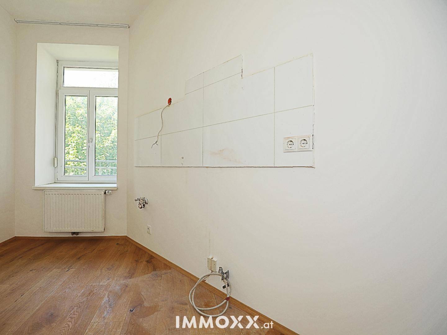 Leerer Küchenbereich mit vorbereiteten Anschlüssen und Fliesen an der Wand, mit Fenster.