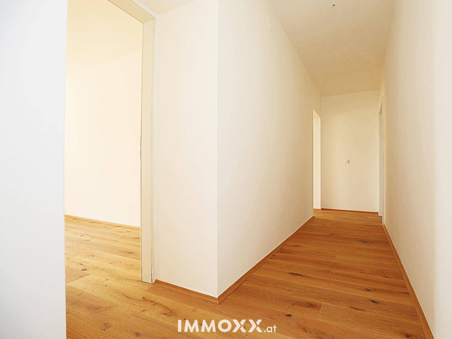 Heller Flur mit Holzboden, der zu weiteren Räumen der Wohnung führt.