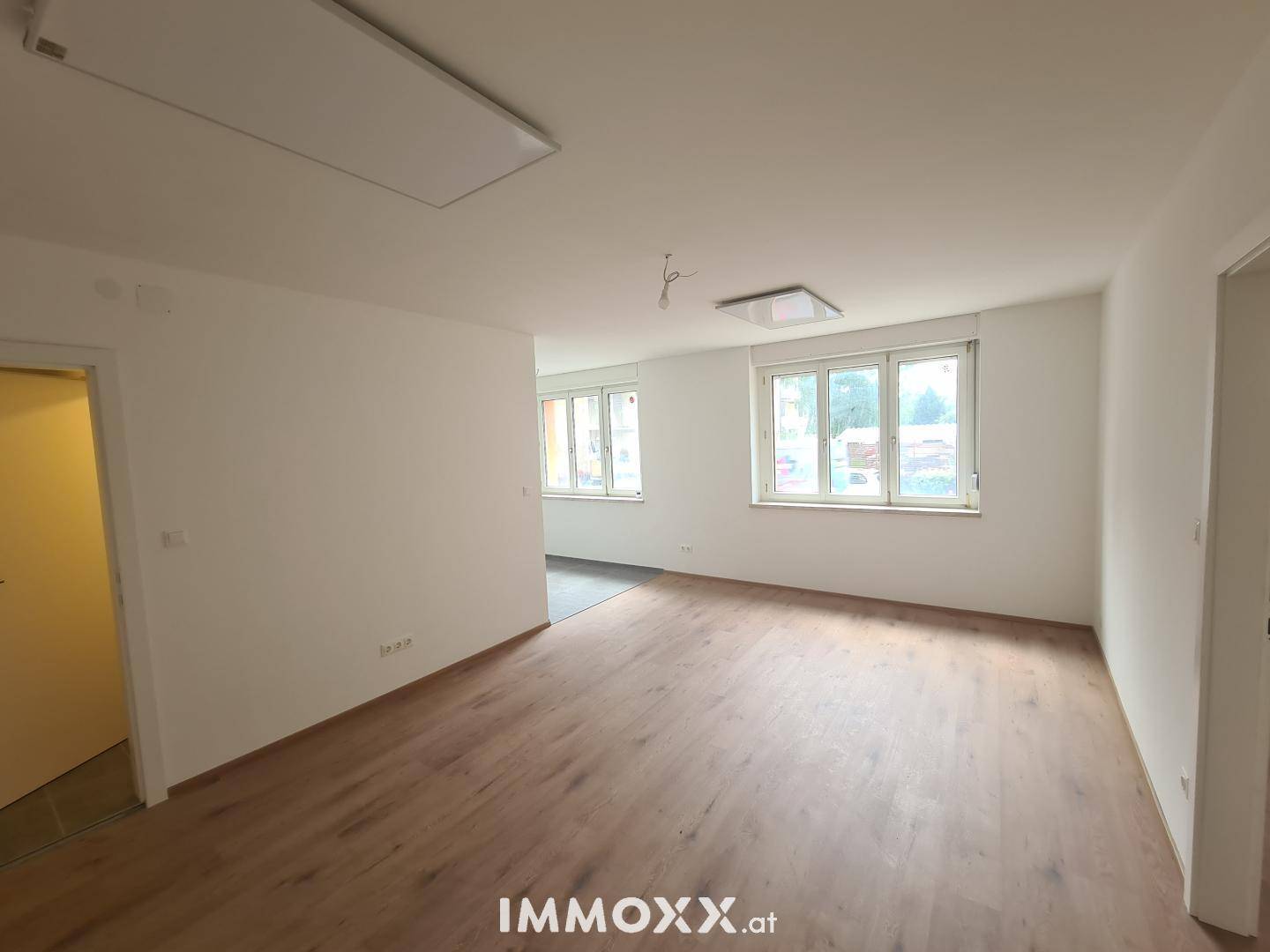 Geräumiges Zimmer mit Laminatboden und zwei Fenstern, die den Raum hell und einladend wirken lassen.