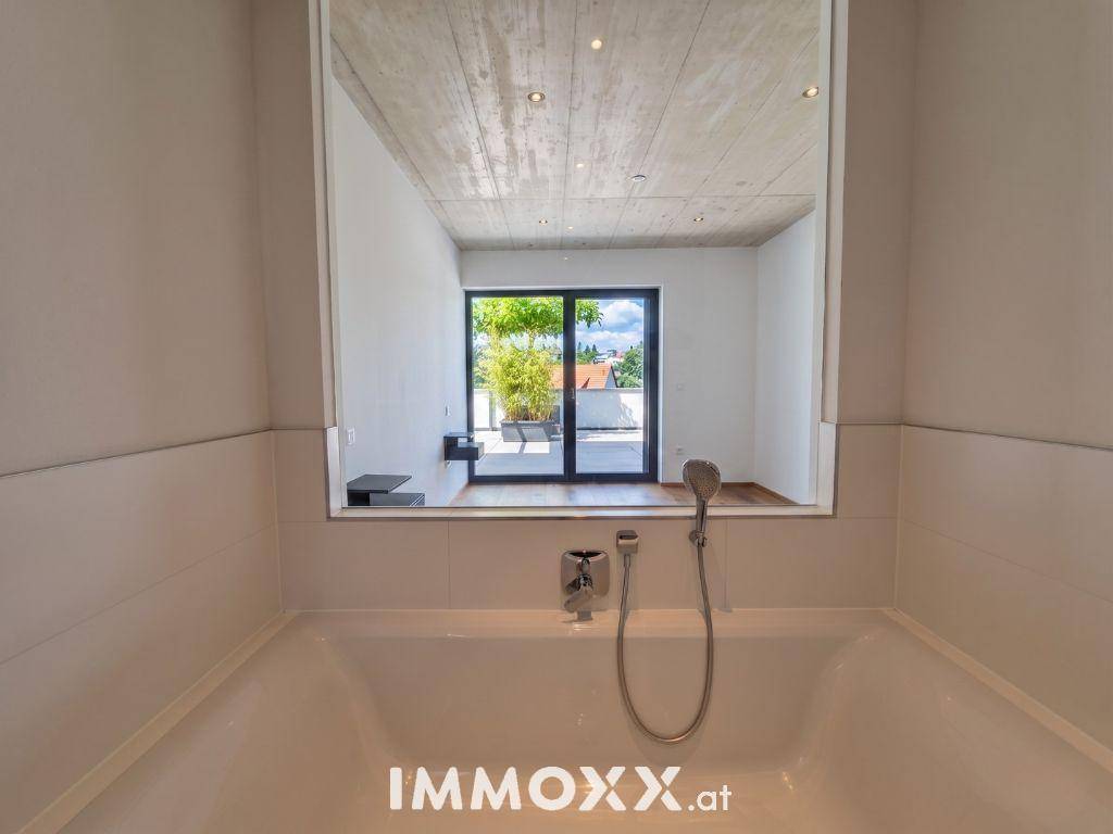 Modernes Badezimmer mit Badewanne und Spiegel, der den Raum reflektiert.