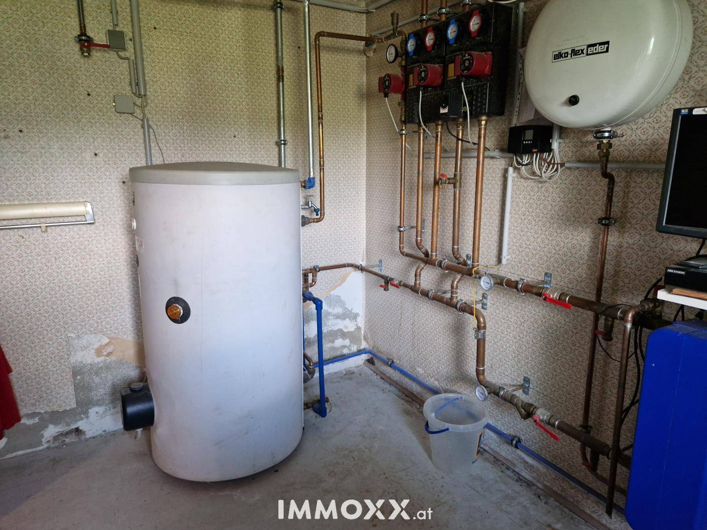 Hauswirtschaftsraum mit Warmwasserspeicher und sichtbaren Rohrleitungen für die Haustechnik.