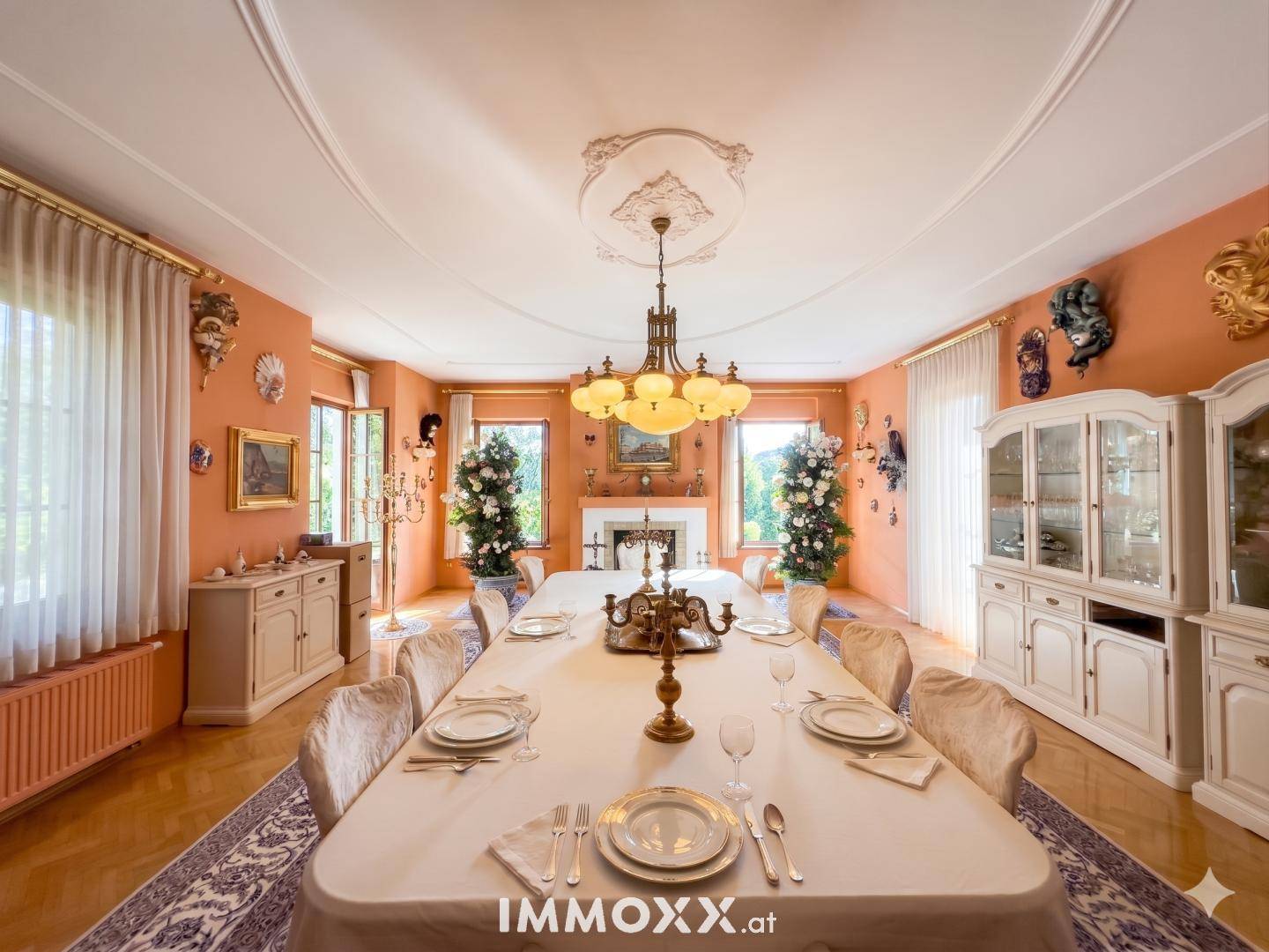 Elegantes Esszimmer mit langem Tisch, Stuckdecke und traditioneller Einrichtung in warmen Farbtönen.