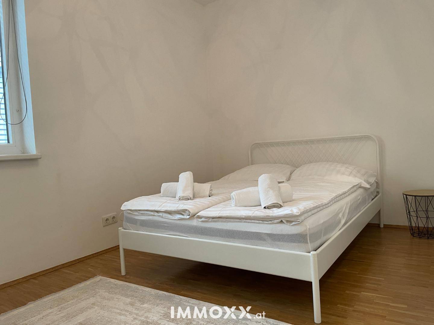 Schlafzimmer mit Doppelbett, Holzboden und einem Fenster für natürliches Licht.