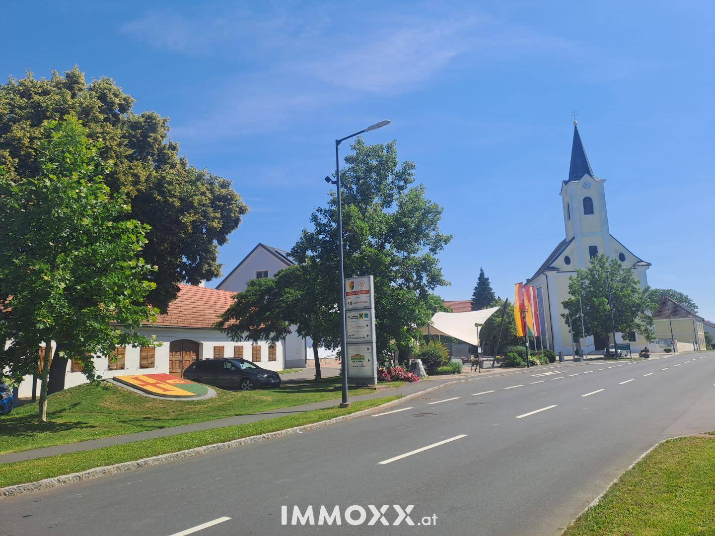 Dorfstraße mit einer Kirche und traditionellen Gebäuden unter klarem blauem Himmel.